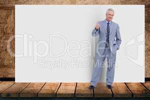 Portrait of senior businessman gesturing while standing against blank billboard in office