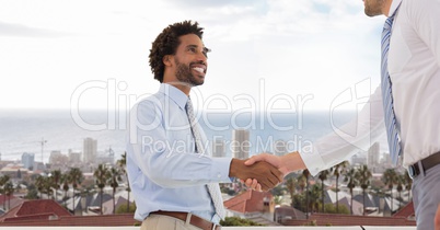 Businessmen doing handshake against city