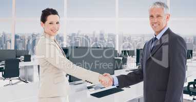 Portrait of confident business partners shaking hands in office