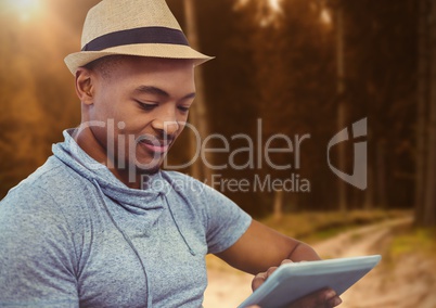 man on tablet in forest trees