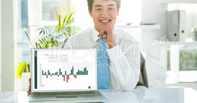 Portrait of businessman with graph on laptop at desk in office