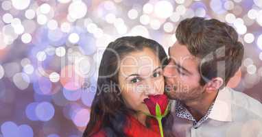 Portrait of woman with rose being kissed by man over bokeh