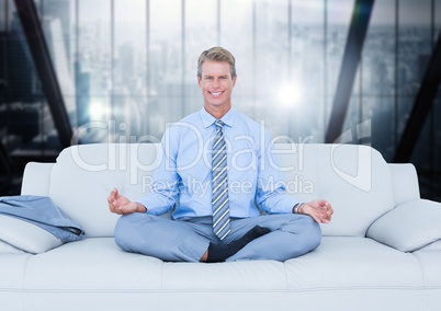 Business man meditating on couch against blurry dark blue window