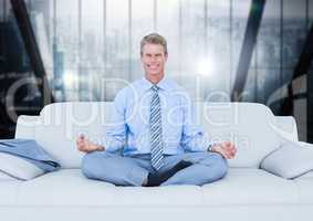 Business man meditating on couch against blurry dark blue window