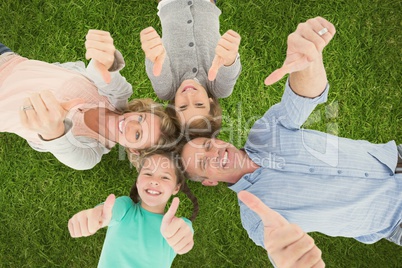Family showing thumbs up sign while lying on grass