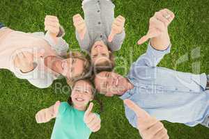 Family showing thumbs up sign while lying on grass