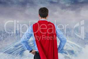 Rear view of businessman wearing super hero cape while looking at city and globe