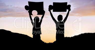 Silhouette children holding puzzle pieces on mountain during sunset