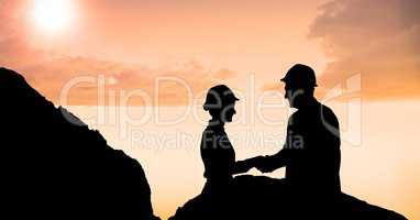 Silhouette male and female professionals shaking hands during sunset