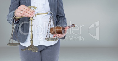 Judge with balance scale and hammer in front of grey background