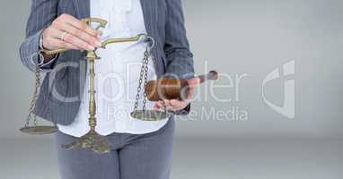 Judge with balance scale and hammer in front of grey background