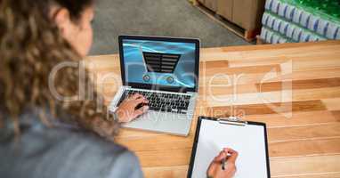 Businesswoman shopping online while writing notes