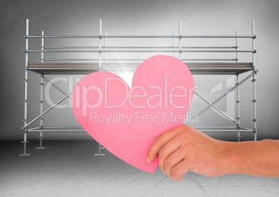 Hand with heart and flare in front of scaffolding in grey room