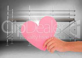 Hand with heart and flare in front of scaffolding in grey room