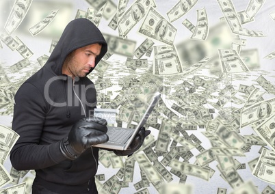 Criminal in hood on laptop in front of lots of money