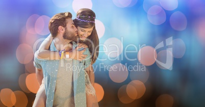Man kissing woman while giving her piggyback ride over bokeh