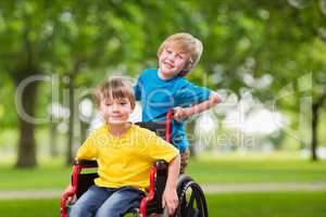Portrait of boy pushing brother in wheel chair
