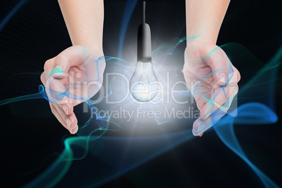 Digital composite image of hand covering electric bulb against black background