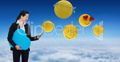 Digitally generated image of emojis flying by businessman using phone in sky
