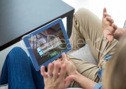 Couple with tablet on the sofa. Screen with login