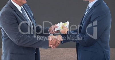 Midsection of businessmen holding money representing corruption concept