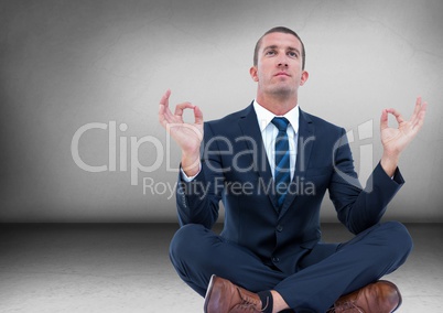 Business man with flare meditating in grey room