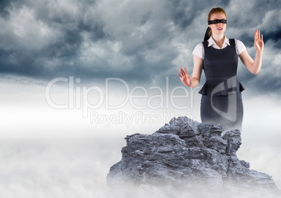 Business woman blindfolded on misty mountain peak against storm clouds
