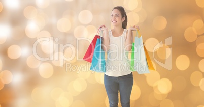 Woman smiling while holding shopping bags over bokeh