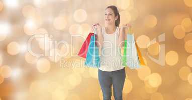 Woman smiling while holding shopping bags over bokeh