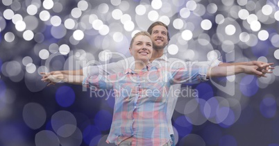 Loving couple with arms outstretched standing against blur background
