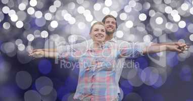 Loving couple with arms outstretched standing against blur background