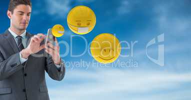 Businessman using smart phones while emojis flying against sky