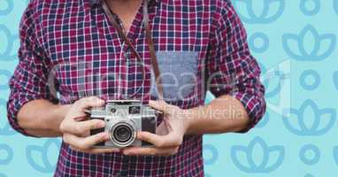 Man mid section with camera against blue floral pattern