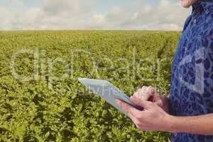 Midsection of man using digital tablet at field against sky