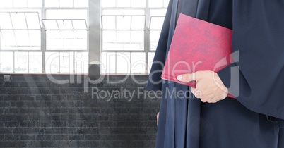 Judge holding book in front of windows and brick wall