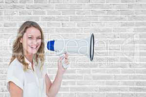 Portrait of smiling woman holding megaphone against brick wall