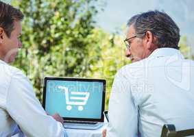 Two men using Laptop with Shopping trolley icon