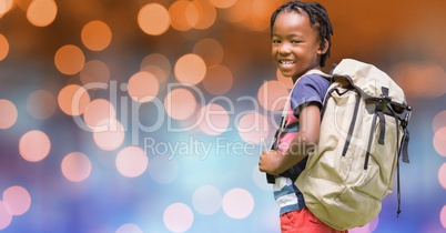 Rear view of school child carrying backpack over bokeh
