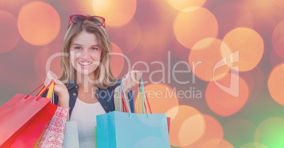 Smiling woman with multi colored shopping bags over bokeh