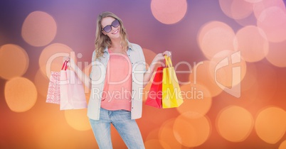 Fashionable woman holding shopping bags over bokeh