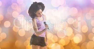 Young music artist singing while holding microphone over bokeh
