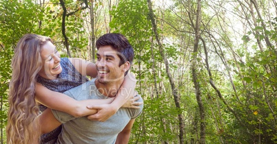 Happy man giving piggy back ride to woman in forest
