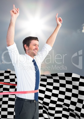 Business man cheering at finish line against sky and sun and checkered flag