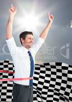 Business man cheering at finish line against sky and sun and checkered flag