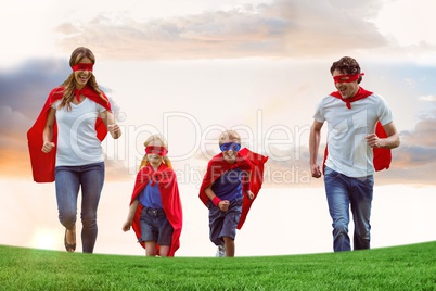 Family wearing capes and eye masks while running on field against sky