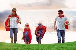 Family wearing capes and eye masks while running on field against sky