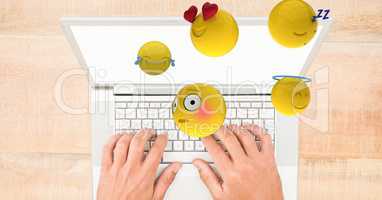 Digital composite image of emojis flying over hands using laptop at table
