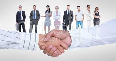 Business people shaking hands with colleagues in background