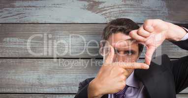 Businessman making finger frame against wooden wall