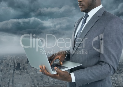 Businessman on laptop with city background